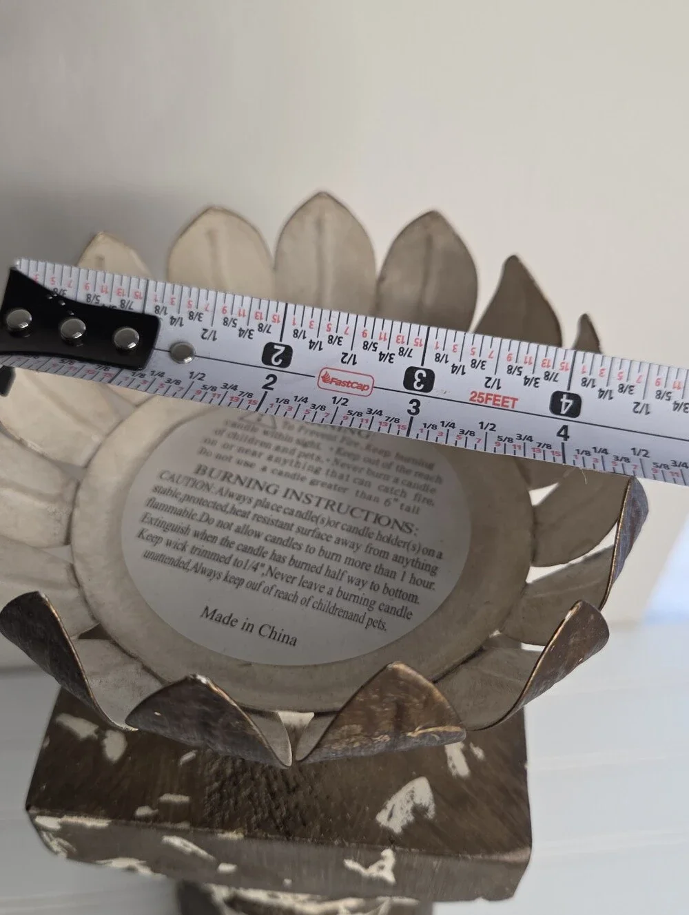 white and gold candlestick features a distressed finish and a lotus-shaped top